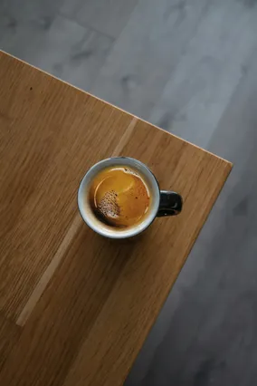 Espresso shot in a small cup on a wooden cafe bench